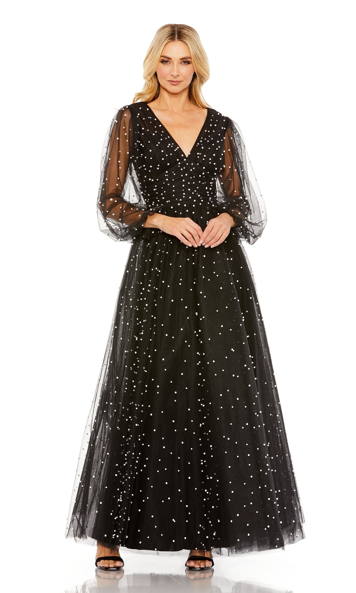 A woman models the Long Formal Dress 20746 by Mac Duggal, featuring a ruched bodice, sheer puffed sleeves, and white polka dots, set against a plain white background.